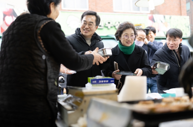 26일 오후 김동연 경기도지사와 정우영 배우자가 설맞이 의왕도깨비시장 방문하여 구매한 전을 다회용기에 포장하고 있다.